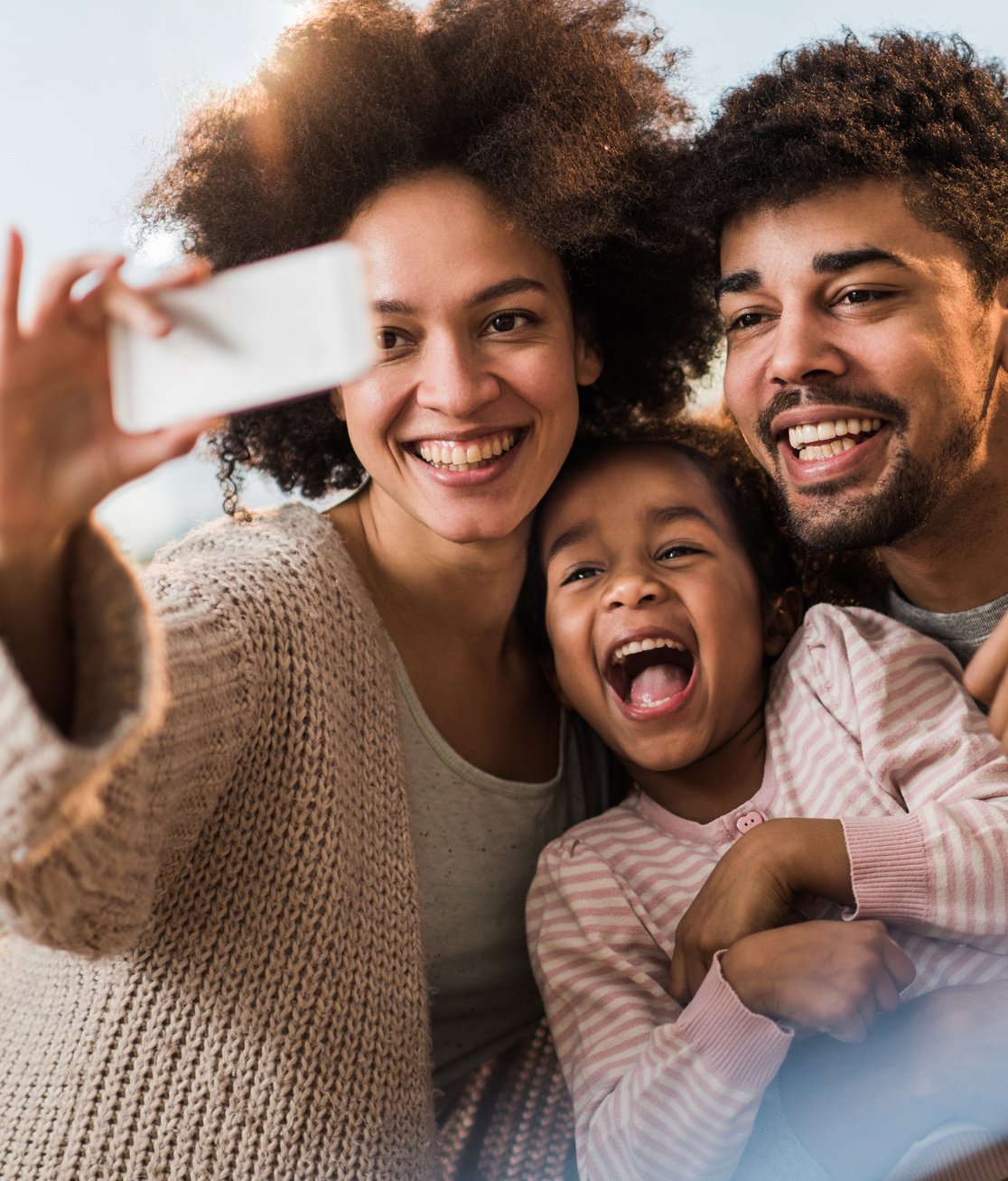 Cheerful African American family having fun while taking a selfie with cell phone.